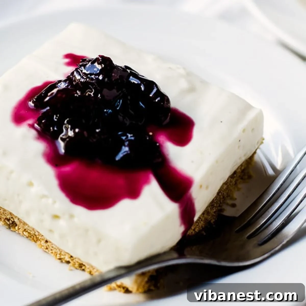 Velvety No-Bake Cheesecake Squares 2 no bake cheesecake bar on a plate with a fork