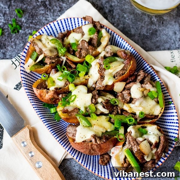 A finished plate of ultimate cheesesteak potato skins garnished with fresh scallions