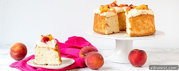 Beautiful homemade Angel Food Cake topped with fresh peaches and whipped cream, ready to serve.