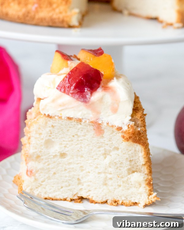 Angel Food Cake with Peach Topping Angel Food Cake being served with generous amounts of poached peaches and whipped cream.