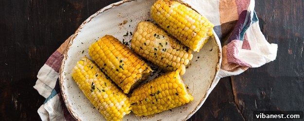 Easy Slow Cooker Corn on the Cob for delicious meals. Two perfectly cooked ears of slow cooker corn on the cob on a white plate, ready to be enjoyed.