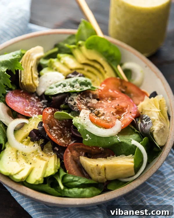 Close-up of creamy Olive Garden style salad dressing in a glass jar with fresh salad ingredients