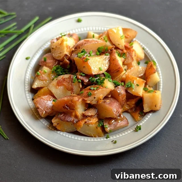 Final plated serving of Slow Cooker Cheddar Bacon Ranch Potatoes, garnished with chives and sour cream.