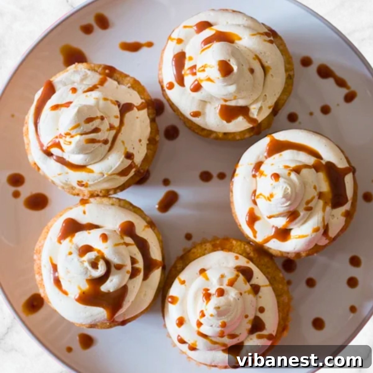Spiced Caramel Apple Cupcakes 4 Moist apple cupcakes with cream cheese frosting and caramel drizzle on top, a perfect autumnal dessert ready to be enjoyed.