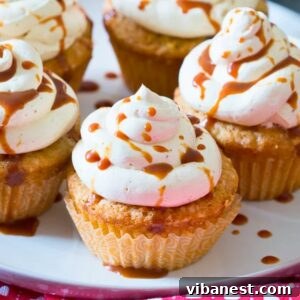 Spiced Caramel Apple Cupcakes 5 close-up of caramel apple cupcakes topped with cinnamon cream cheese frosting and drizzled with caramel sauce.