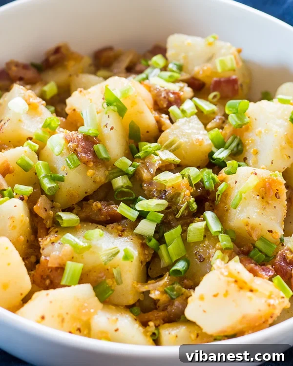 german-potato-salad-2.jpg Warm German potato salad with crispy bacon and fresh chives, served in a bowl.
