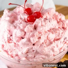 Top-Tier Thanksgiving Side Dishes 10 A bowl of light pink, fluffy cherry salad, garnished with whipped cream and maraschino cherries, a sweet and festive addition.