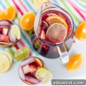 Overhead view of a pitcher and glasses filled with virgin sangria, surrounded by fresh lemons, limes, and oranges