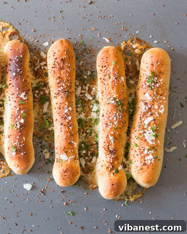 cheese-stuffed-garlic-breadsticks-3.jpg A plate of freshly baked cheese stuffed garlic breadsticks with a side of dipping sauce