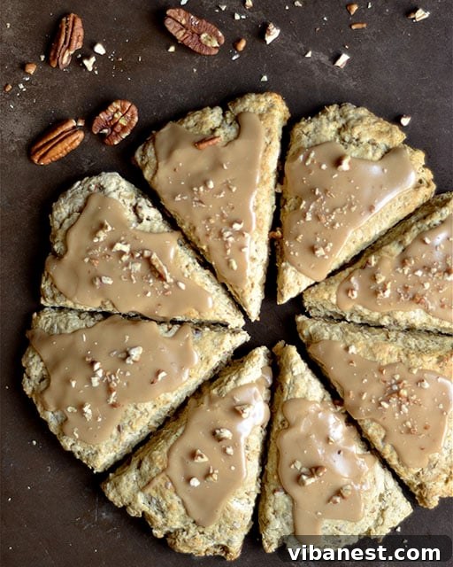 maple-oat-pecan-scones-2.jpg Close-up of a homemade Maple Oat Pecan Scone, showcasing its flaky texture and rich ingredients