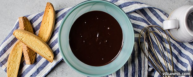 Rich chocolate ganache being poured, ready to glaze a dessert