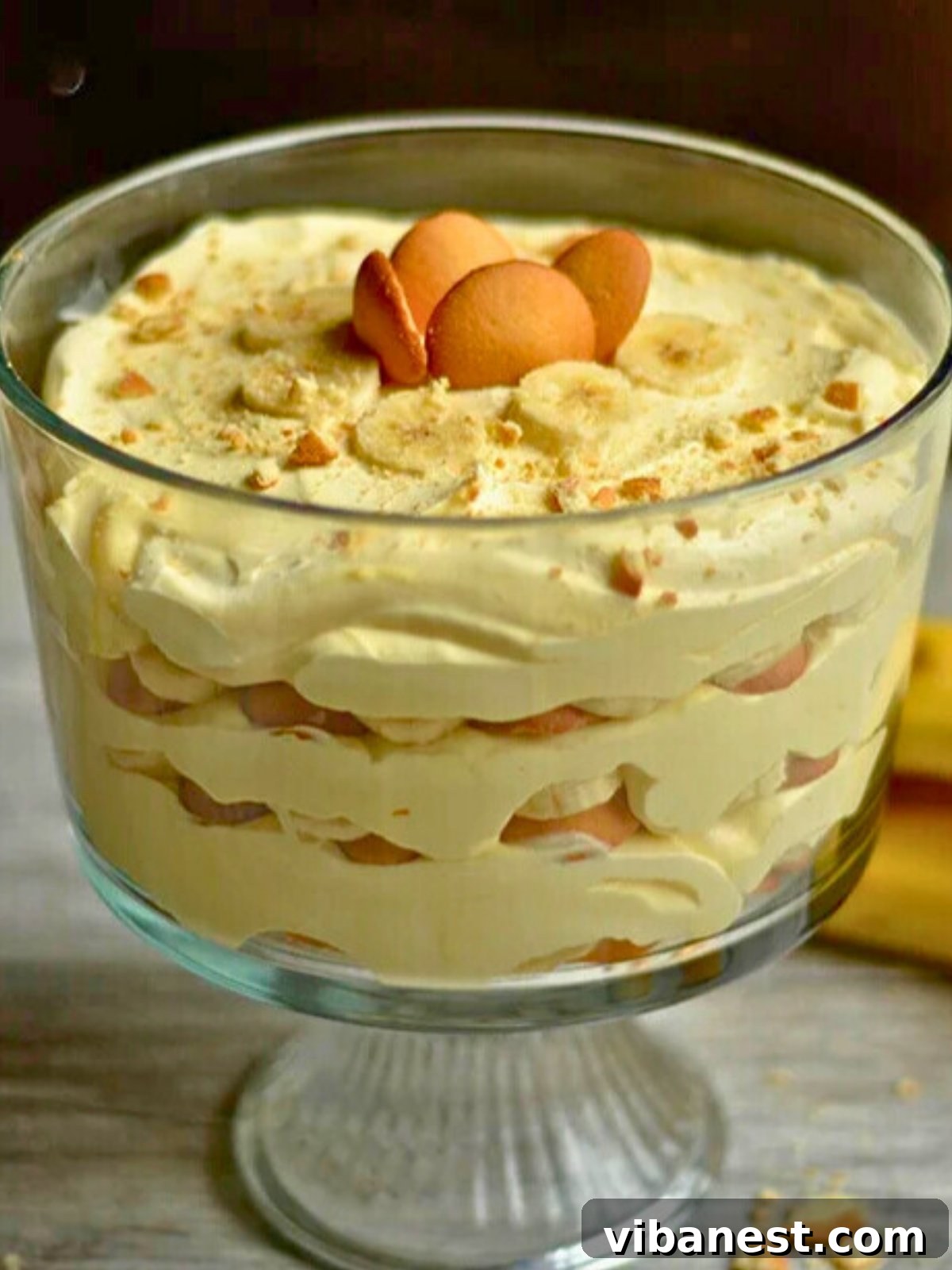 Golden Banana Dream 5 Banana pudding dessert with vanilla wafers layered in a trifle dish, ready to be chilled.