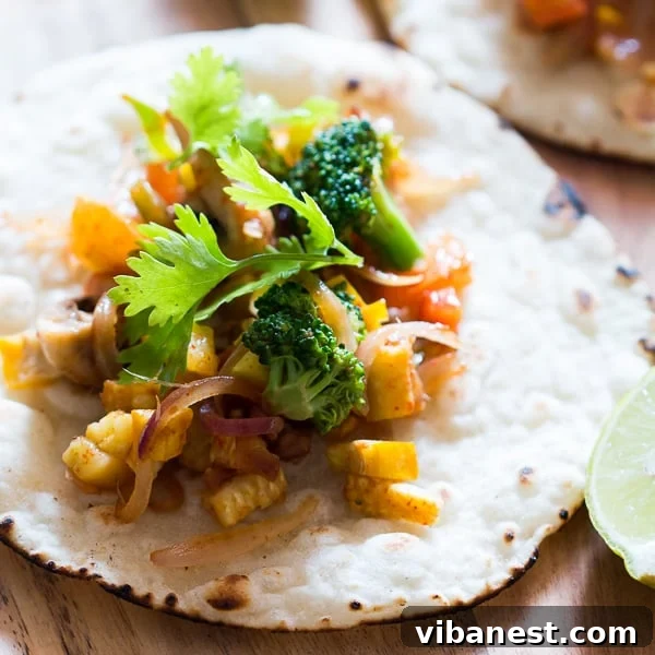 A beautifully arranged serving of healthy vegetarian tacos, overflowing with colorful ingredients and cheese, garnished with fresh cilantro.