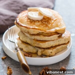 close-up of easy banana pancakes on a plate, garnished with fresh banana slices and a drizzle of maple syrup