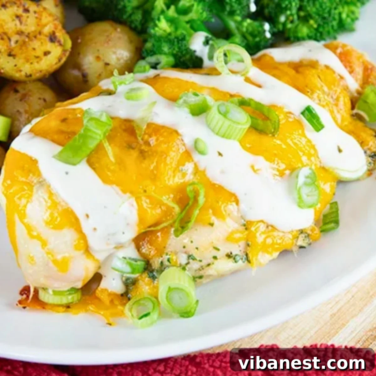 Juicy Baked Ranch Chicken Dinner Close-up of juicy baked ranch chicken breasts, seasoned with a ranch mix and served on a plate with roasted potatoes and fresh broccoli.