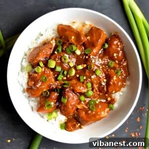 Easy Slow Cooker General Tso Chicken 6 bowl of slow cooker general Tso's chicken served over white rice and garnished with green onions.