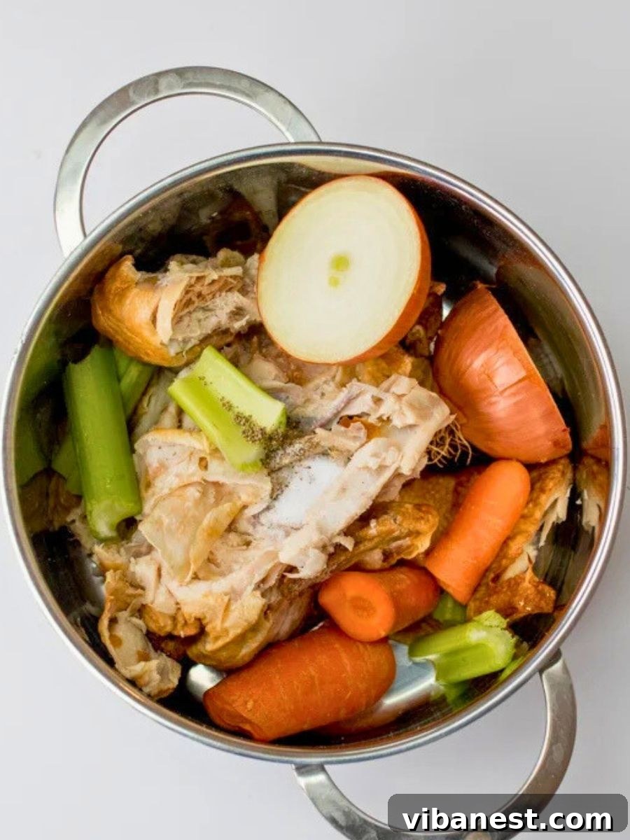 Mastering Homemade Chicken Stock 5 Raw chicken bones, onions, carrots, and celery arranged in a large stockpot before simmering to make chicken stock.