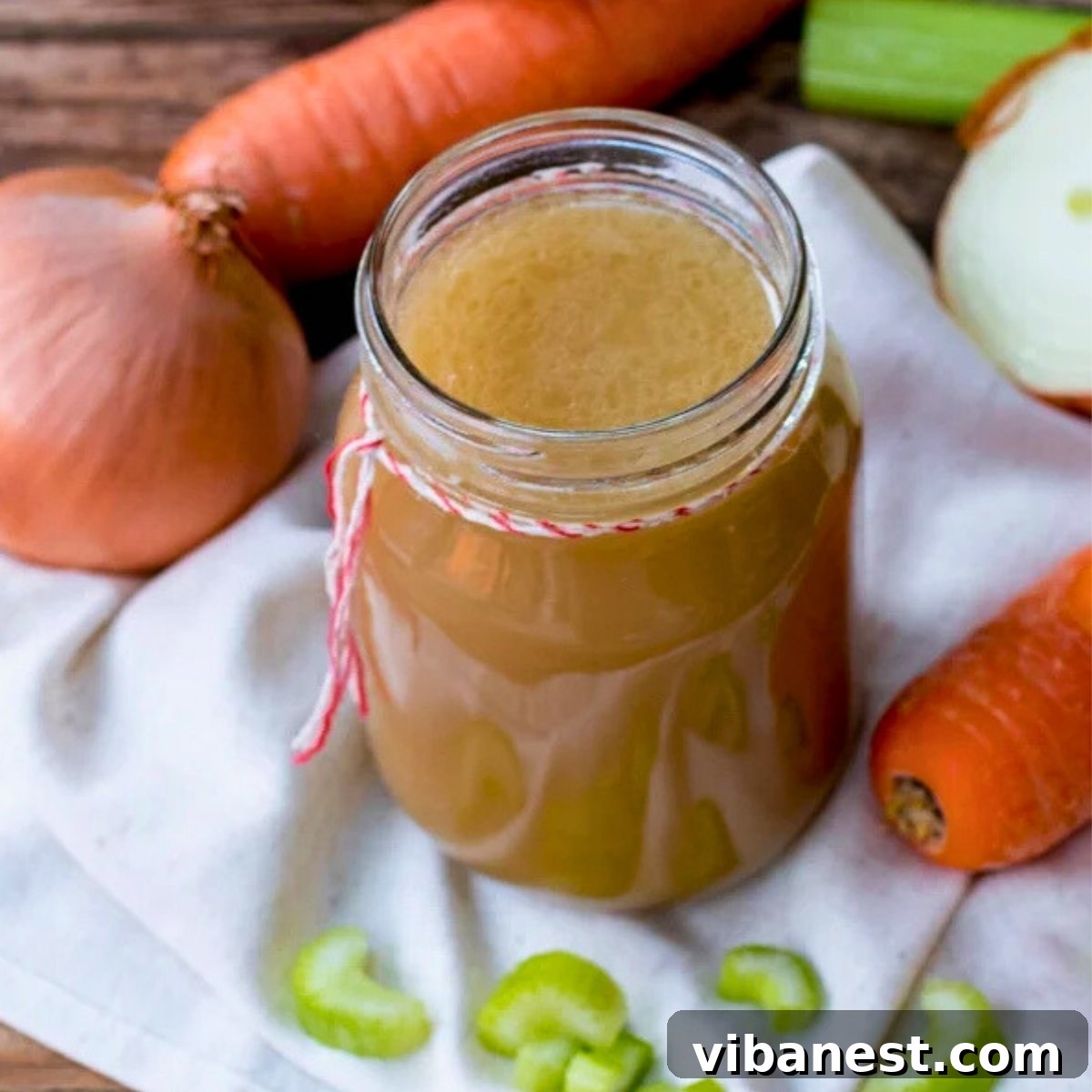 Mastering Homemade Chicken Stock 8 Rich homemade chicken stock in a glass jar with fresh vegetables in the background