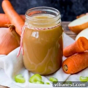 Homemade chicken stock in a glass jar with vegetables in the background