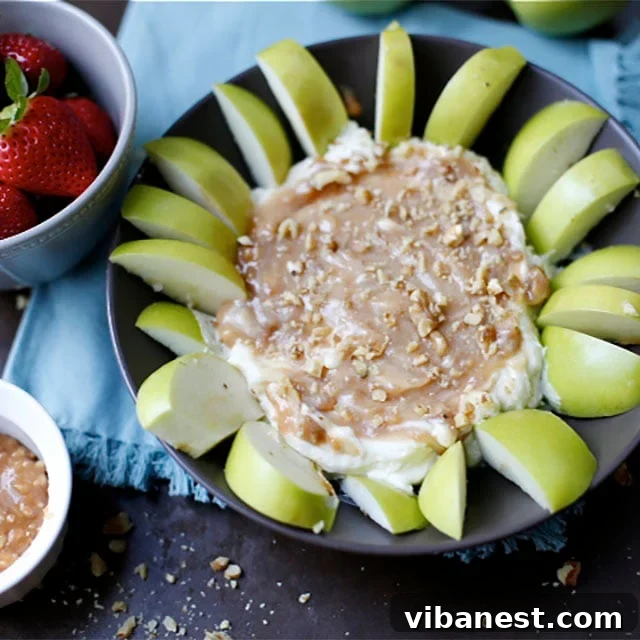Freshly made Caramel Apple Pecan Cheesecake Dip garnished with pecans and served with apple slices