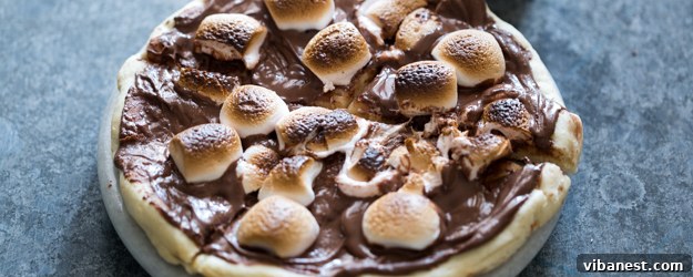 Delicious S'mores Chocolate Pizza with melted chocolate and toasted marshmallows on a baking sheet