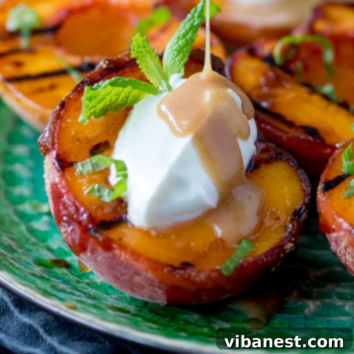 Smoky Sweet Grilled Peaches with Cinnamon Caramel Glaze 5 close up of grilled peaches drizzled with cinnamon caramel sauce and garnished with fresh mint leaves