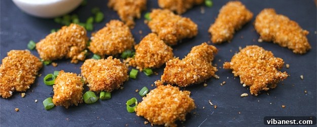 Delicious Baked Chipotle Popcorn Chicken bites on a serving platter, garnished with fresh herbs and a dipping sauce.