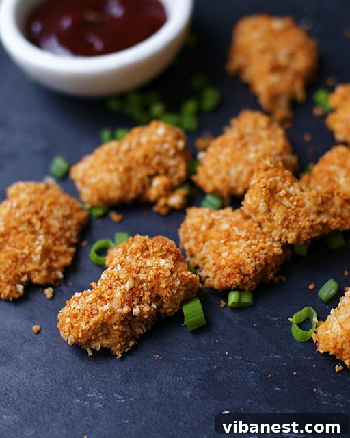 Chipotle Popcorn Chicken - Crispy Texture Close-up photo showing the golden-brown, crispy exterior of baked chipotle popcorn chicken pieces on a baking sheet.