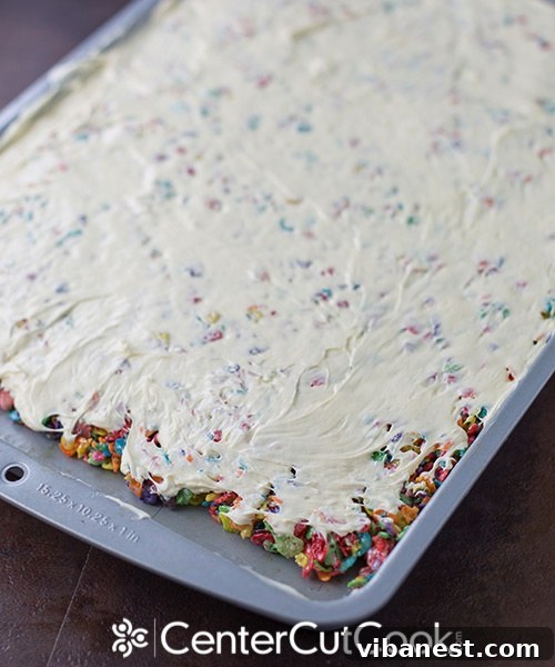 Fruity Pebbles Treat Base in Pan, Ready for Frosting The vibrant Fruity Pebbles cereal mixture, firmly pressed into a greased jelly roll pan, ready for its next step