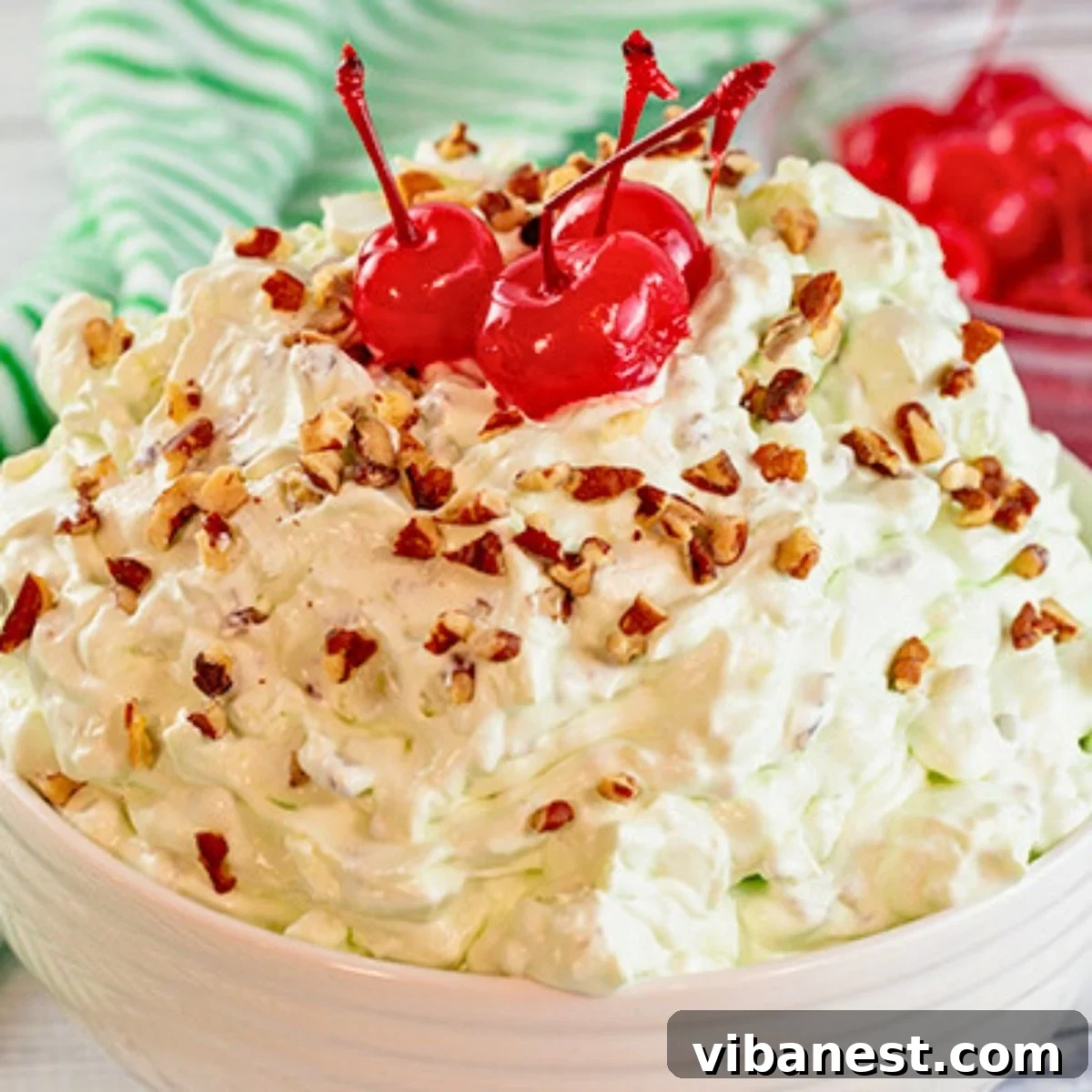 Creamy Pistachio Cloud 2 A large bowl of creamy green Watergate salad, garnished with mini marshmallows and chopped pecans, ready to be served.