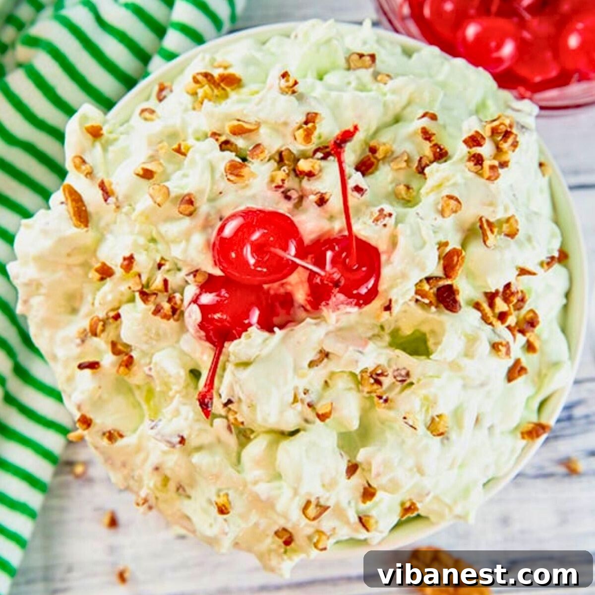 Creamy Pistachio Cloud 4 Overhead view of a large bowl of easy pistachio fluff dessert, garnished with nuts and marshmallows, ready for serving.