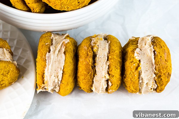 Hand holding a pumpkin whoopie pie, showcasing the generous cinnamon cream cheese frosting