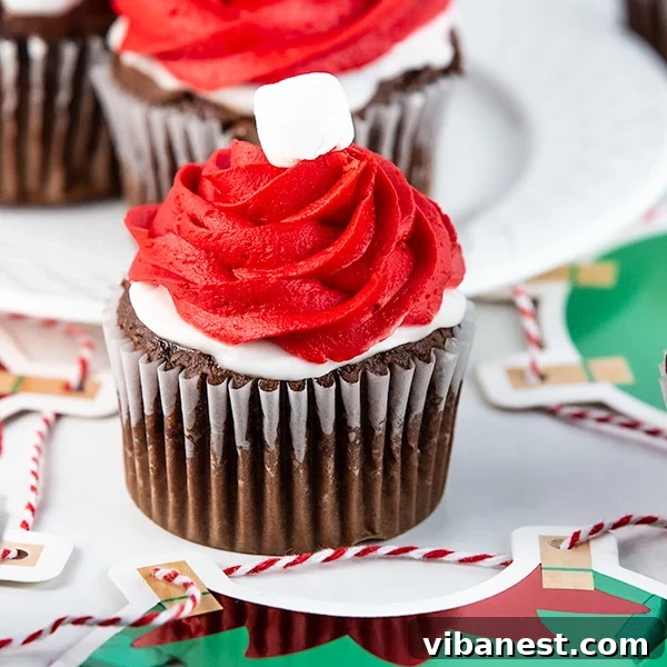 Elf-on-the-Shelf-Cupcakes-Gift Two festive Elf on the Shelf cupcakes adorned with red frosting and mini marshmallows, ready for holiday gifting.