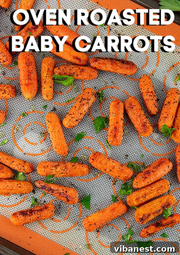 oven-roasted-baby-carrots-3.jpg Close-up of perfectly oven-roasted baby carrots on a baking sheet, showcasing their caramelized edges and vibrant orange color.