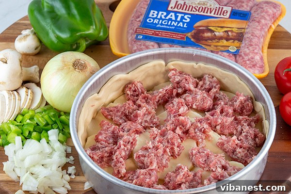 Layer of raw Johnsonville Brat sausage over mozzarella cheese in deep-dish