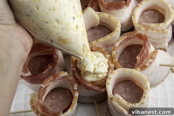 air-fryer-bacon-wrapped-kielbasa-bites-8.jpg Piping cheesy ranch filling into bacon-wrapped kielbasa cups