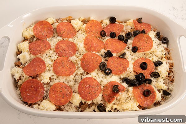 Layering Cheese and Toppings on Pizza Casserole Pizza casserole mixture topped with mozzarella and pepperoni