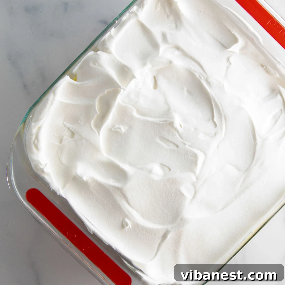 Strawberry Layered Delight 12 spreading cool whip over pudding layer in strawberry lasagna