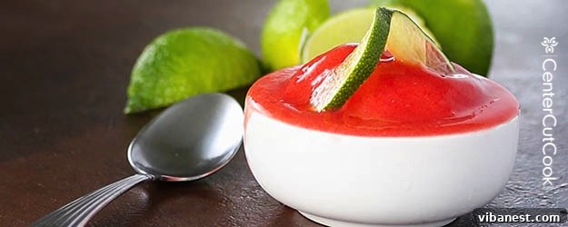 Vibrant red strawberry lime sorbet in a stylish bowl, garnished with fresh mint and lime slices, set on a bright background