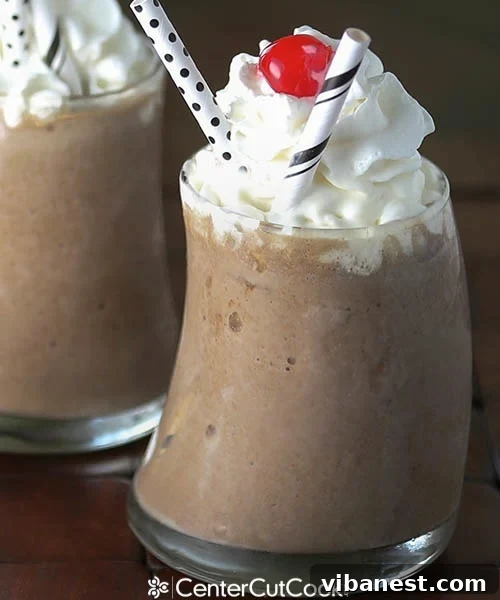 Creamy Chocolate Peanut Butter Milkshake Close-up of a chocolate peanut butter milkshake in a clear glass with a straw, garnished with whipped cream and a cherry