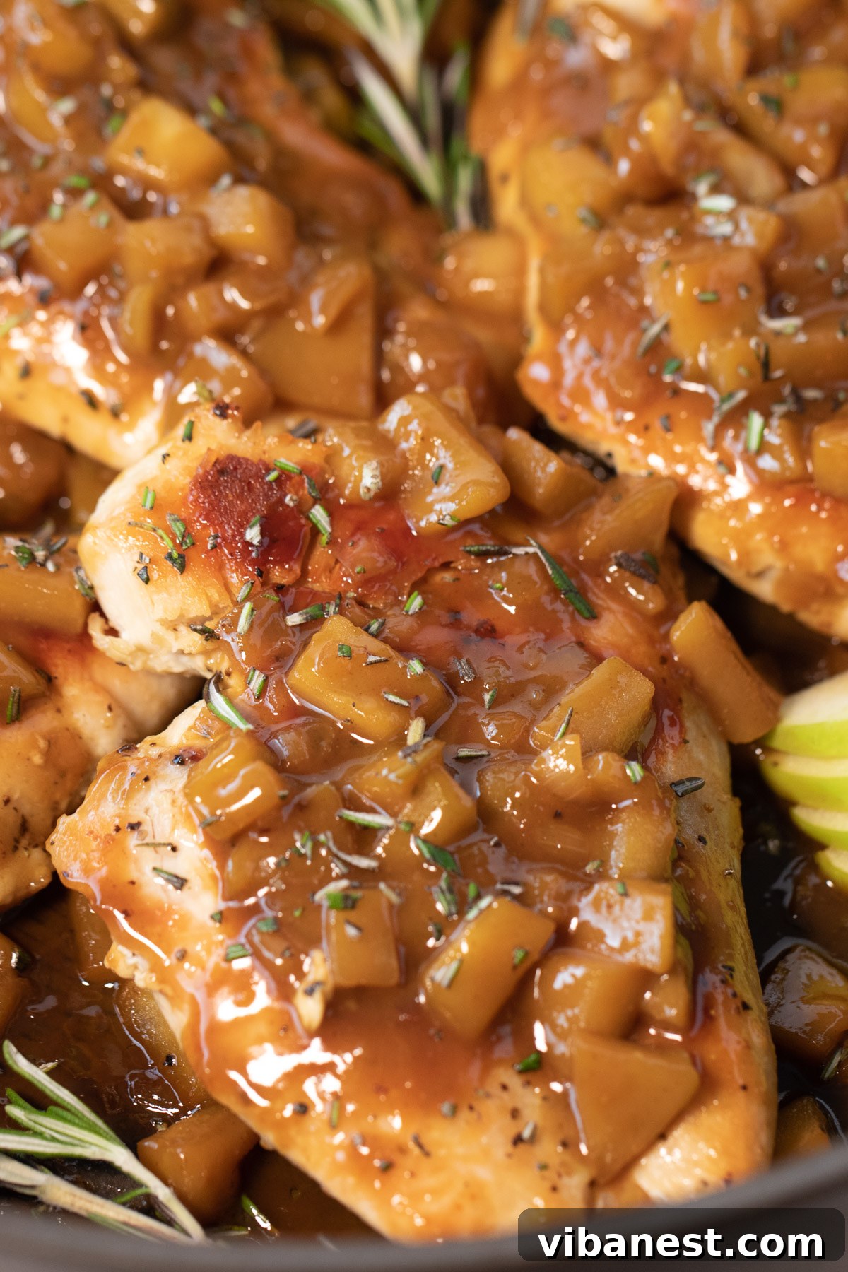 Harvest Skillet Chicken with Apple Cider Glaze 4 Close-up of a beautifully plated chicken breast with a generous serving of apple cider sauce, adorned with tender apples and fresh rosemary, ready to be enjoyed as a comforting fall meal.