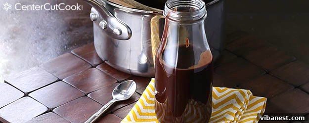 Rich, dark homemade hot fudge generously drizzled over ice cream, showcasing its smooth texture
