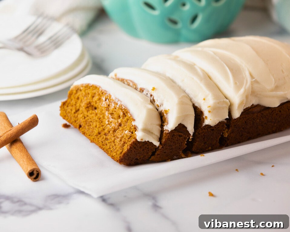 Decadent Pumpkin Bread with Creamy Cheesecake Topping 2 Sliced pumpkin bread with cream cheese frosting on a plate, ready to be enjoyed.