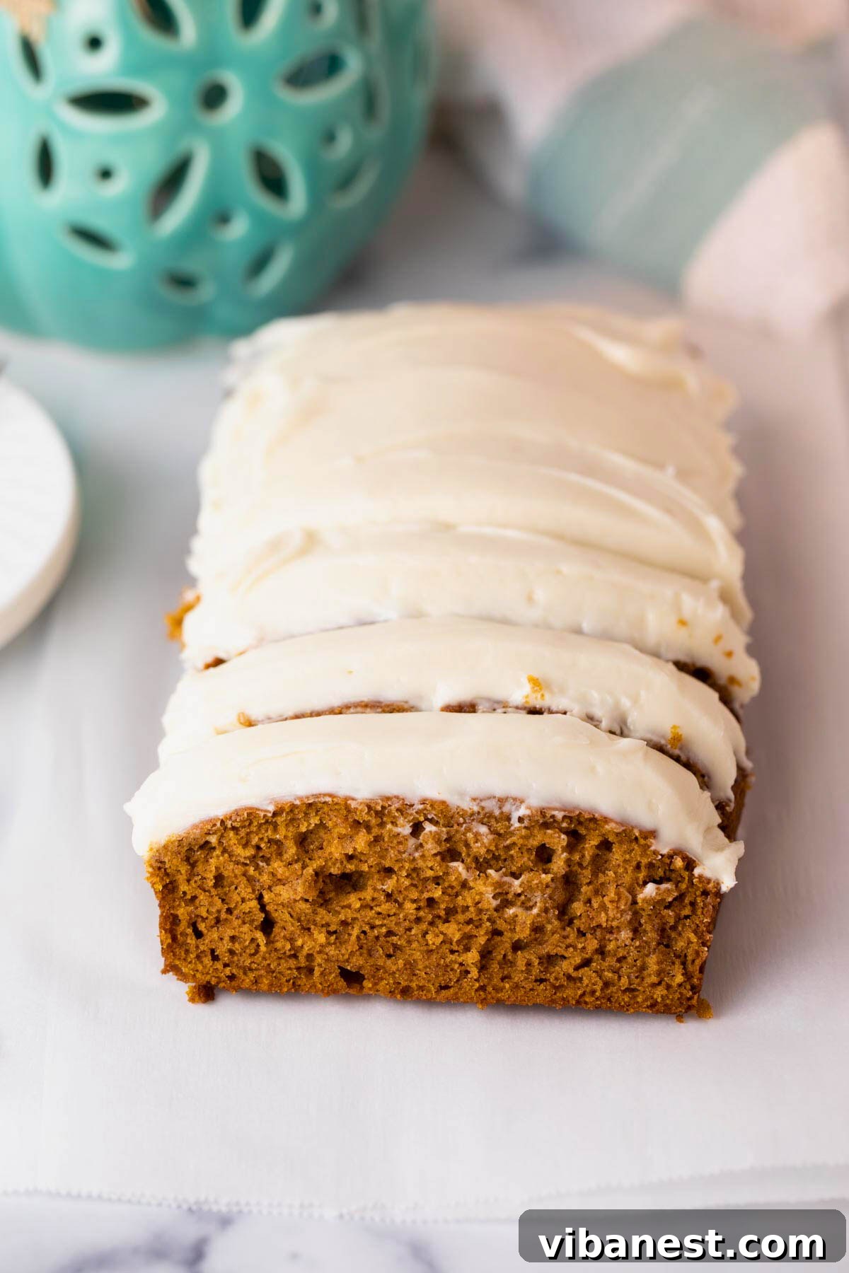 Decadent Pumpkin Bread with Creamy Cheesecake Topping 4 Several slices of pumpkin bread with cream cheese frosting arranged beautifully on a serving plate.