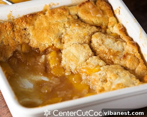 fresh peach cobbler 5.jpg Close-up of a serving of fresh peach cobbler topped with a dollop of whipped cream, on a white plate.