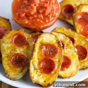 Cheesy Pizza Potato Bites 15 A plate of golden-brown pizza potato skins, generously topped with melted mozzarella cheese, slices of spicy pepperoni, and a sprinkle of Italian seasoning. Served alongside a small bowl of rich marinara sauce for dipping, ready to be enjoyed.