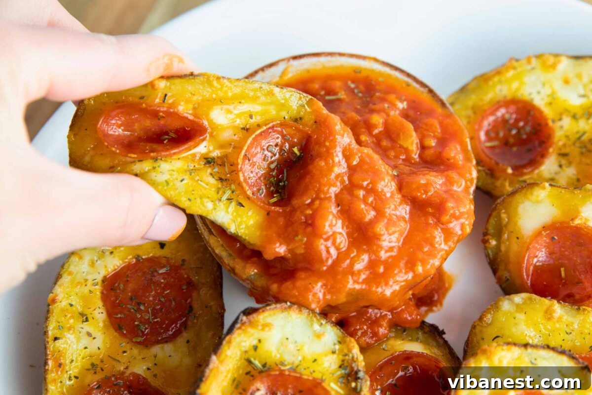 Cheesy Pizza Potato Bites 4 A close-up shot of a single, mouth-watering pizza potato skin, showcasing its cheesy interior and crisp edge, just after being dipped in rich pizza sauce.