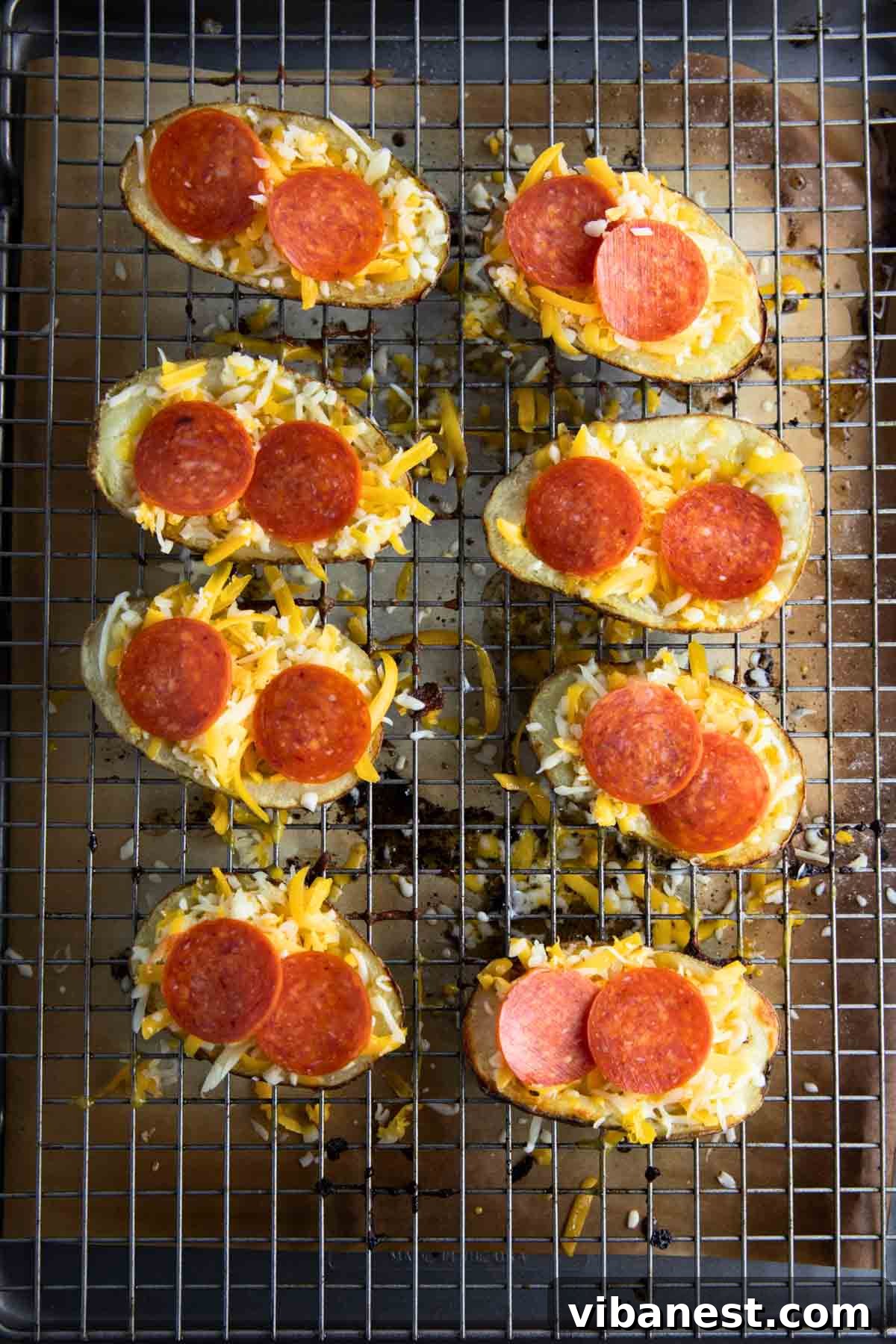 Cheesy Pizza Potato Bites 10 A baking sheet displaying multiple potato skins meticulously arranged, generously topped with an abundance of cheese, pepperoni, and a medley of other pizza toppings, poised for their final bake.