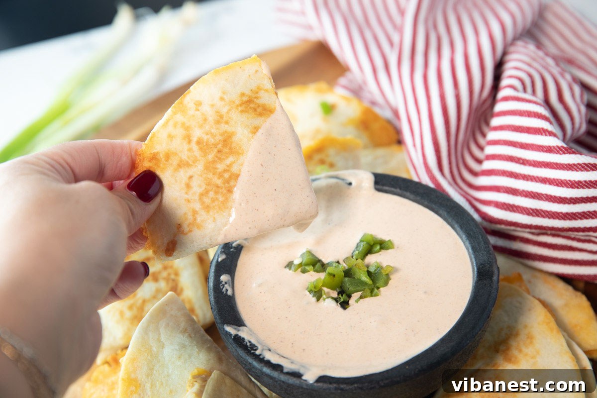 Whip Up Perfect Stovetop Quesadillas 6 A woman's hand gracefully dips a crispy, golden quesadilla into a rich, creamy bowl of queso, highlighting the perfect texture and delicious pairing.