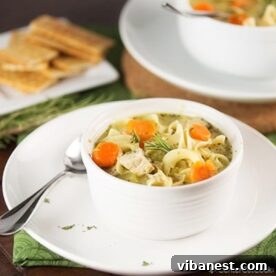 A comforting bowl of chicken noodle soup, with a spoon resting invitingly beside it.